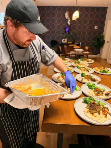 Chef Zak plating a dinner service of herb crusted chicken in an Asheville home